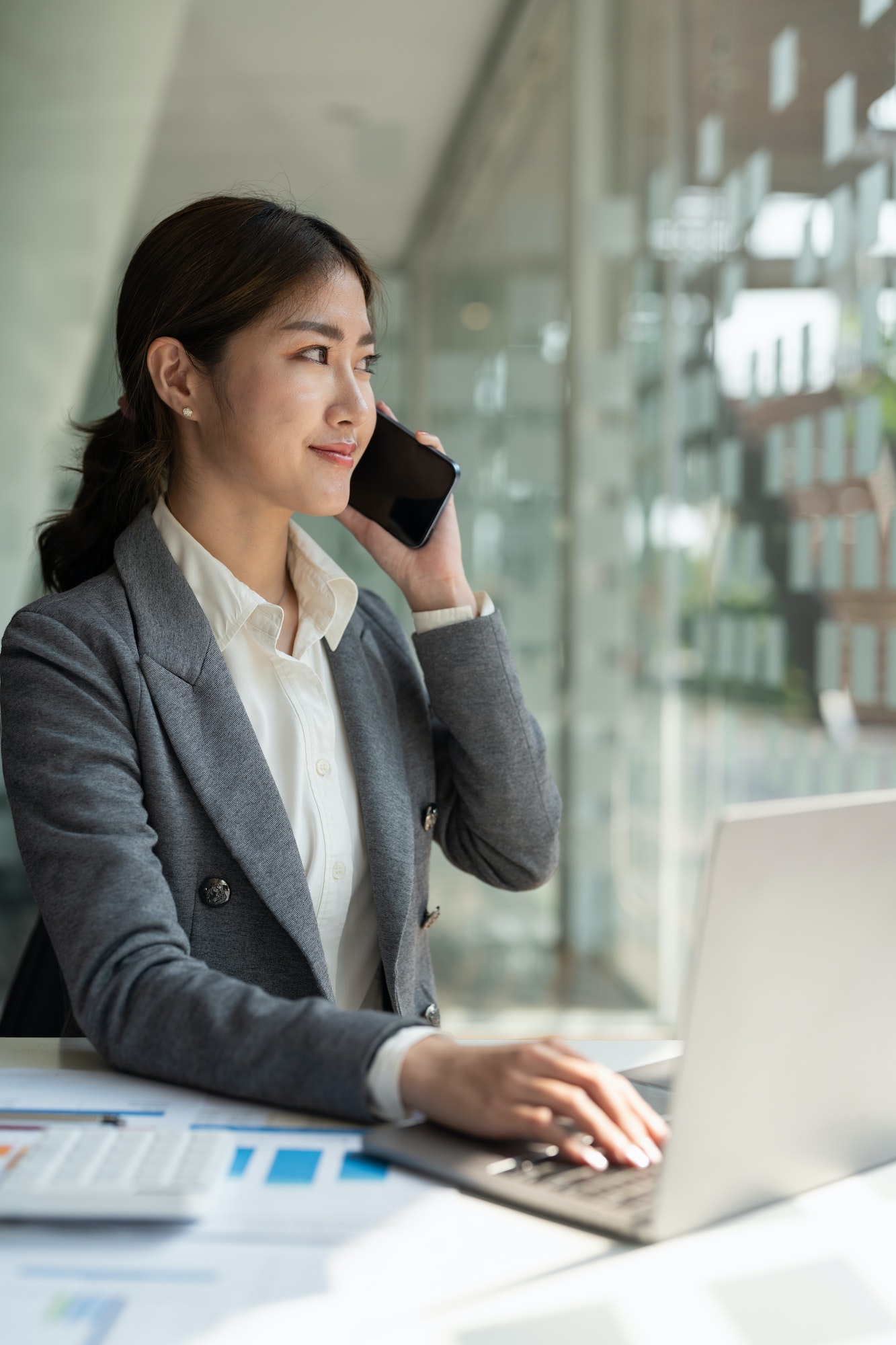Confident business asian woman in talking consultant on mobile phone at modern office